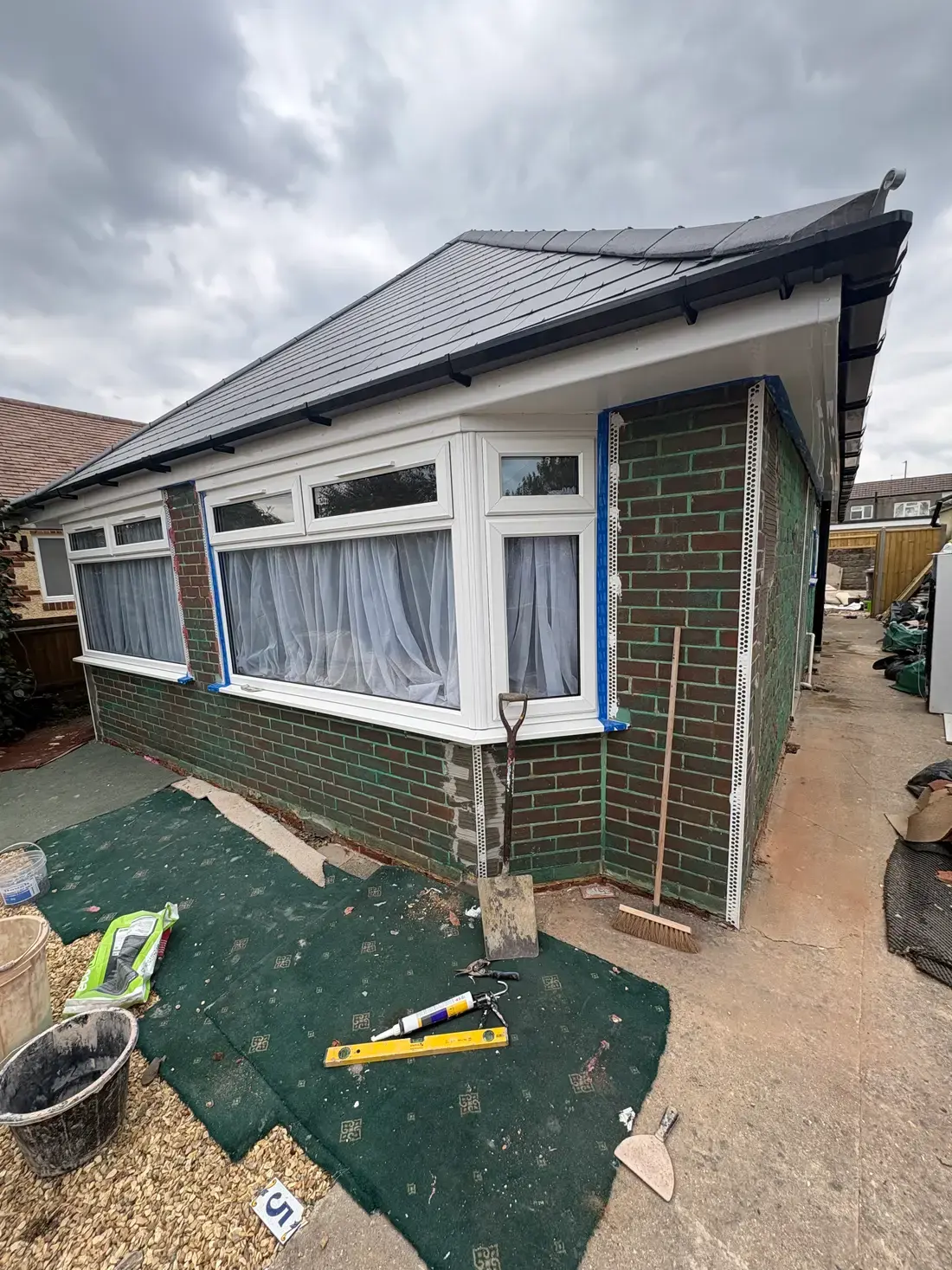 A Pearl Plastering pebble dash strip in progress with bead corners installed on a Dorset bungalow